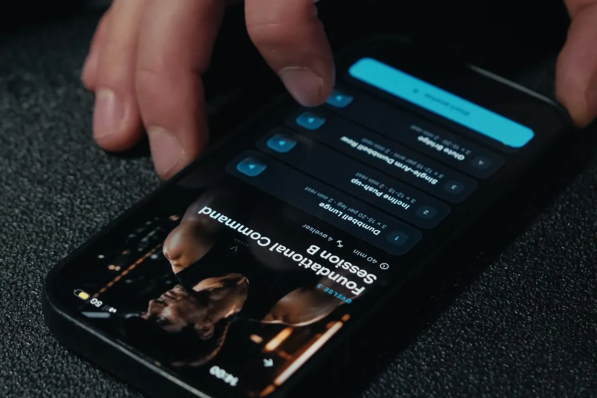 A hand tapping a workout session in the VISOR app, phone lying on a gym mat